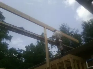 Carpenter setting a ridge beam over a new addition frame — Ice Dam Removal by Roofing Brothers in Randlett