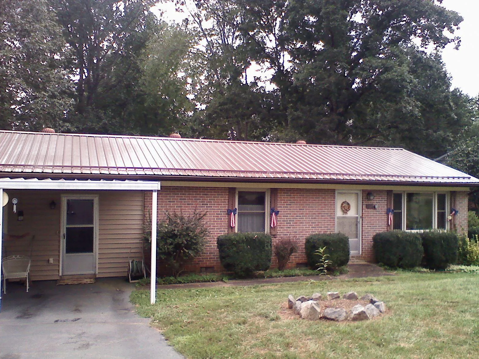Bronze metal roof and carport on a brick ranch home — Roof Repair work by our crew in Randlett