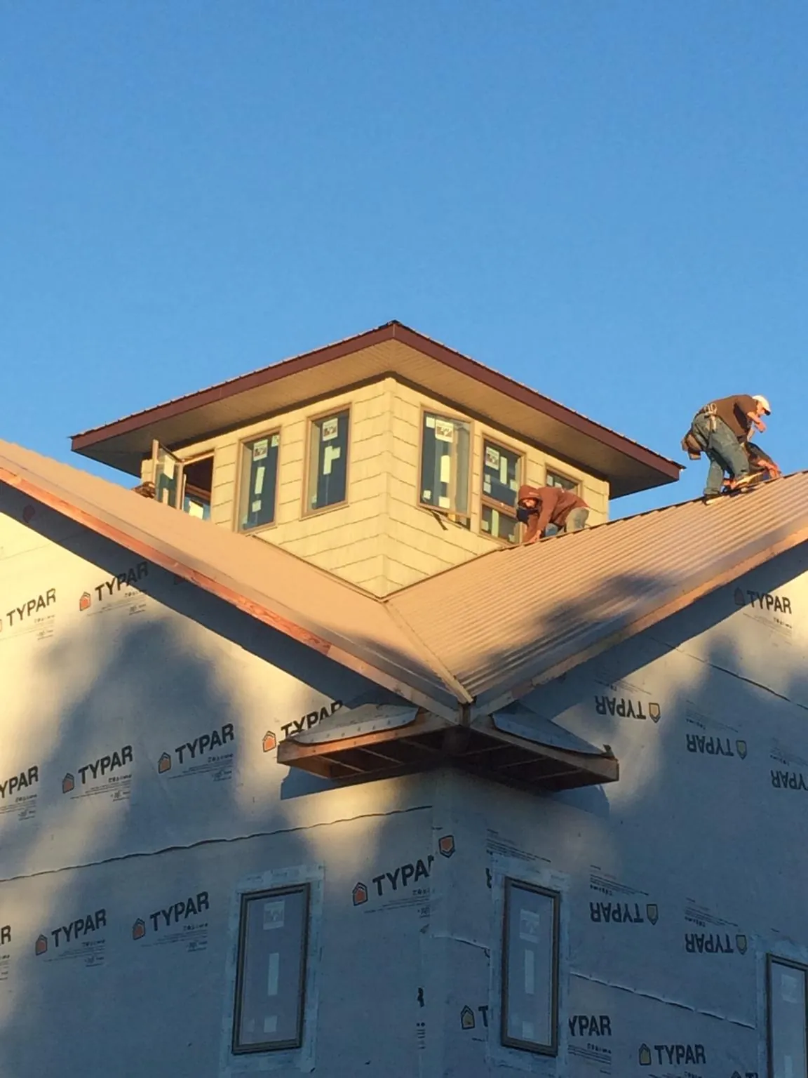 Roofers working around a rooftop cupola on a new metal roof at sunset — Roof Waterproofing in Randlett by Roofing Brothers